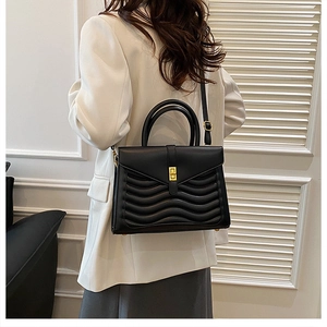 Detail of wavy quilted texture and golden twist lock on black professional handbag
