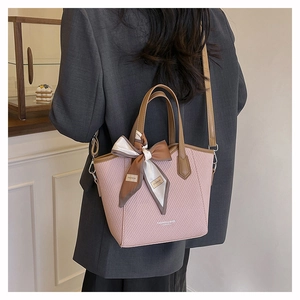 Sac seau rose tissé avec poignées marron et un foulard en soie sur la lanière