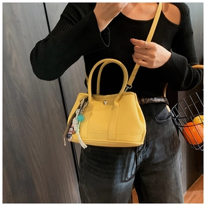 Sac seau en cuir jaune tendance avec fermoir en métal et breloque tressée colorée