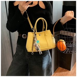 Détail du sac seau en cuir jaune grainé avec doubles poignées et accessoire de mode