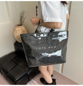 Dettaglio della borsa tote nera lucida con trama stropicciata e scritta TOTE BAG