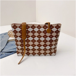 Detail of the diamond quilted pattern and brown leather straps on a large tote bag