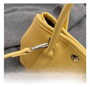 Détail d'un sac à main jaune en cuir grainé avec crochet en métal argenté poli