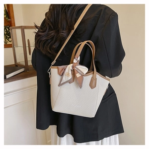 Détail du sac seau tissé avec bordure en cuir et foulard porté par le mannequin