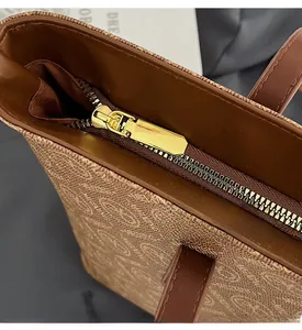 Close-up of smooth gold-tone zipper and vintage brown monogram pattern on large tote bag