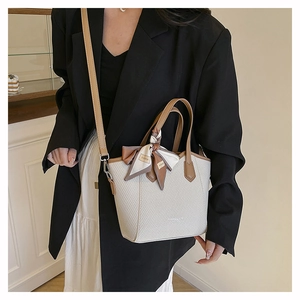 Détail d'un sac seau tissé avec bordure en cuir et ruban décoratif pour un look bureau