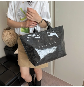 Dettaglio della borsa tote nera lucida con scritta TOTE BAG bianca e finitura chic