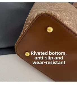 Detailed view of bottom rivets on a brown leather tote bag with sturdy stitching