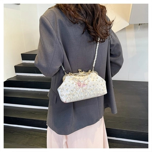 Woman wearing white pearl beaded shell bag with pink butterfly and pearl chain strap