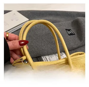 Gros plan du sac à main jaune en cuir grainé avec des poignées supérieures arrondies