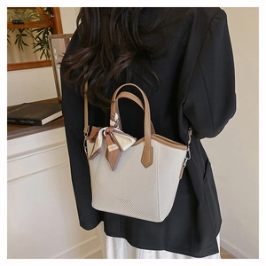 Détail du sac cabas beige tissé avec poignées en cuir et décoration en foulard