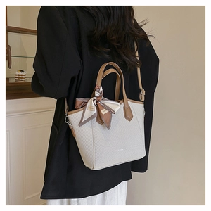 Détail de la texture tissée et de la poignée en cuir du sac seau couleur crème
