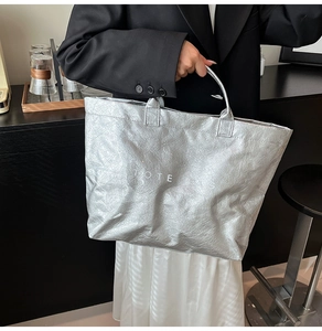 Dettaglio della borsa tote in carta DuPont argento con trama stropicciata e testo TOTE