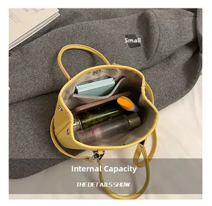 Vue de dessus de l'intérieur du sac seau en cuir jaune montrant sa grande capacité et poches