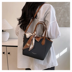 Détail du sac cabas noir avec poignées en cuir marron et foulard en soie décoratif