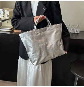 Dettaglio borsa tote argento metallizzato con texture stropicciata e scritta