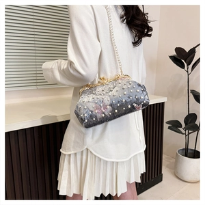 Detail of grey velvet evening shell bag with pearl handle and butterfly embroidery on model