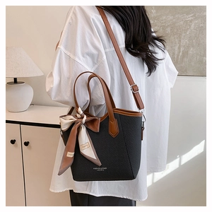 Détail du sac seau minimaliste avec texture tissée, poignées cuir et foulard en soie