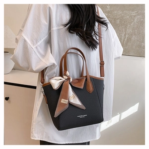 Détail du sac seau gris avec poignées en cuir marron et foulard en soie décoratif