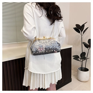 Detail of grey-blue velvet shell bag featuring butterfly embroidery and pearl accents