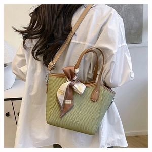 Détail du sac seau tissé vert avec garniture en cuir marron et foulard en soie élégant