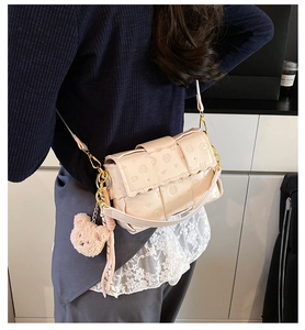Détails du sac beige avec motifs animaliers, chaîne dorée et pendentif ourson