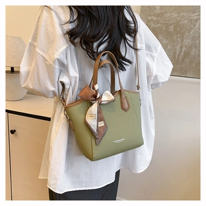 Sac seau tissé vert avec poignées en cuir marron et détail de foulard en soie décoratif