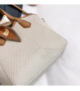 Détail du sac cabas tissé beige avec poignées en cuir marron et nœud décoratif