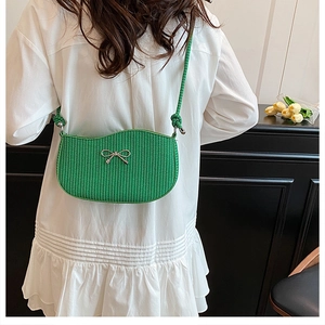 Detailed view of grass green woven crossbody bag with a metallic silver bow clasp
