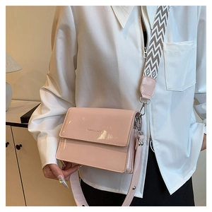 Detail of pink patent leather crossbody bag with geometric woven wide shoulder strap