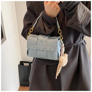 Détail du sac tissé bleu clair avec chaîne dorée, gaufrage chiot et breloque ours en peluche