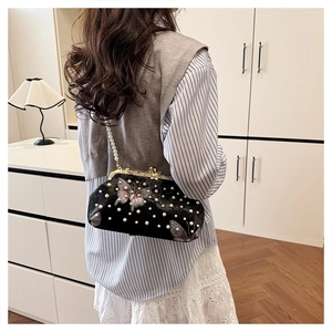 Close-up of black shell bag with pink butterfly embroidery and elegant pearl accents