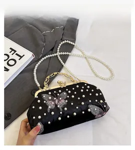 Detail of velvet evening bag with pearl chain, butterfly embroidery and gold clasp