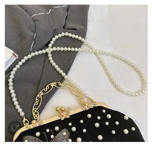 Detail of velvet shell bag with butterfly embroidery, pearl strap and golden handle