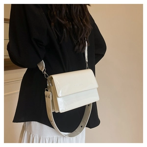 Side-back view of a white patent leather shoulder bag with a wide adjustable strap