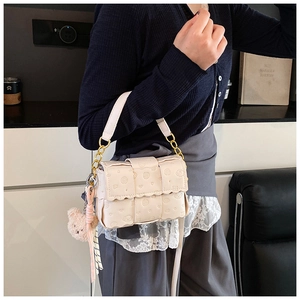 Détail du petit sac bandoulière beige gaufré avec breloque ours et chaîne dorée