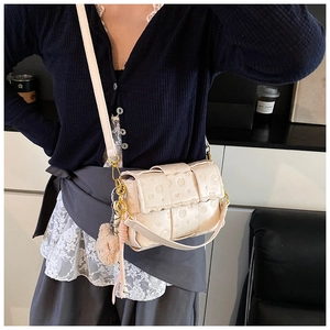 Détail du sac bandoulière tressé crème avec gaufrage chien et pendentif ours