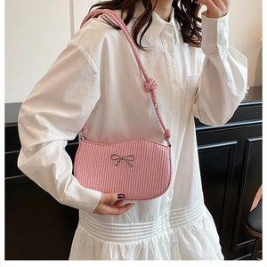 Detail of pink woven shoulder bag with silver bow accent and thick rope strap