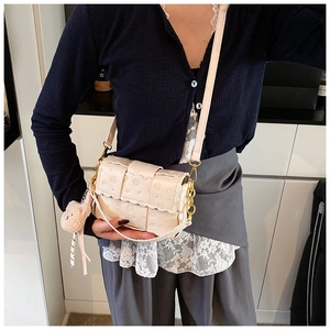 Détail d'un sac bandoulière tressé crème avec motif gaufré et pendentif ours en peluche
