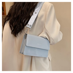 Rear view of a light blue patent leather crossbody bag showing the fashion logo and wide strap
