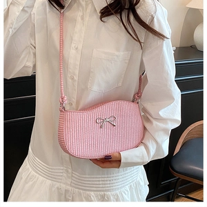 Detail of pink woven shoulder bag featuring a silver metal bow and textured pattern