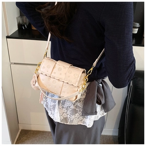 Détail d'un sac bandoulière rose matelassé avec chaîne dorée et breloque en peluche