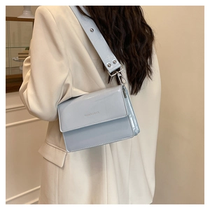 Close-up of light blue patent leather crossbody bag showing glossy texture and strap detail