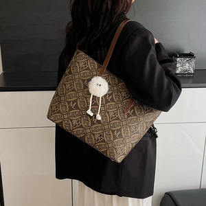 Classic brown tote bag with letter pattern and cute plush charm on a model