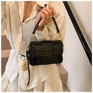 Détail du sac à main noir matelassé avec motifs cœurs et poignée en chaîne dorée chic