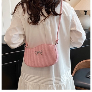 Vista posteriore di una modella con borsa a tracolla rosa testurizzata e fiocco argento