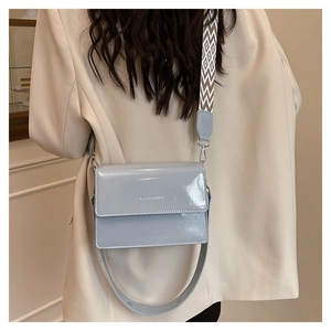 Detail view of light blue patent leather crossbody bag with wave pattern strap