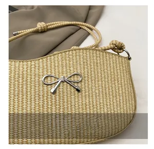 Detail shot of the woven straw bag featuring a silver metal bow buckle and rope strap
