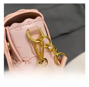 Détail du cuir PU gaufré rose avec chaîne dorée et texture à motifs de cœurs