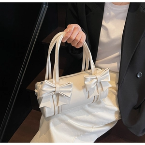Detail of a creamy white cylindrical bow bag with elegant double ribbon decoration